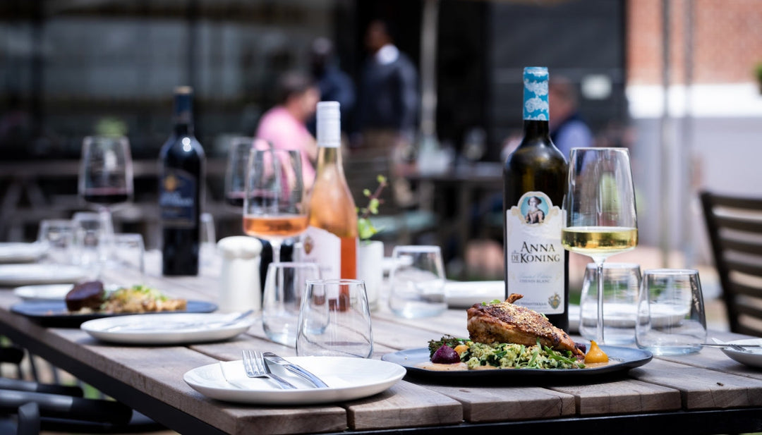 A dining table set with plates of gourmet food and wine at Groot Phesantekraal