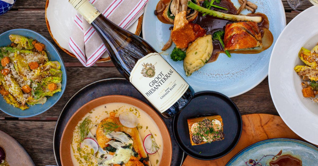 Wine bottle with plated dishes and shared meal on a table in Durbanville Winery 